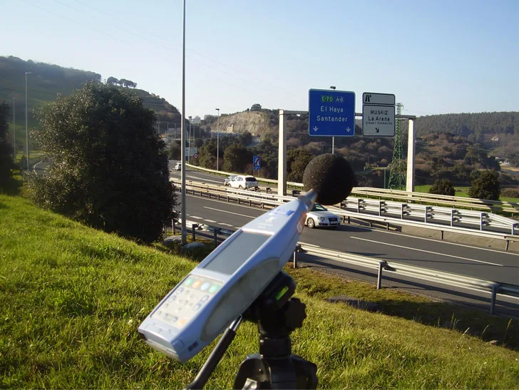 Sonómetro sobre trípode midiendo el ruido de tráfico junto a una autovía